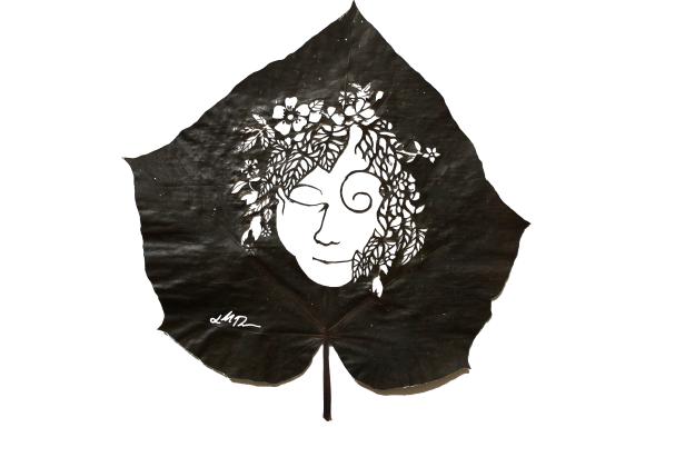 Ein geschnitztes Gesicht mit Blumen im Haar auf einem Blatt.