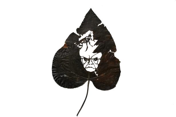 Ein Blatt mit einer ausgeschnittenen Darstellung eines Gesichtes und einer Insektenfigur.