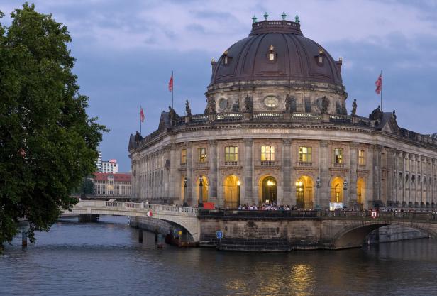 Das Bode-Museum in Berlin, gesehen von der Wasserseite mit einer Brücke im Vordergrund.