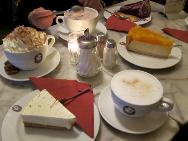 Auf einem Tisch stehen verschiedene Kaffeespezialitäten und Kuchenstücke.