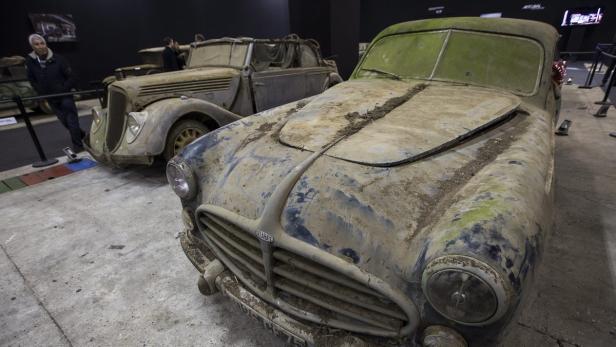 Zwei alte, verstaubte Delahaye-Autos stehen in einer Ausstellung.