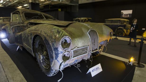 Ein verrosteter Oldtimer steht auf einer Bühne.