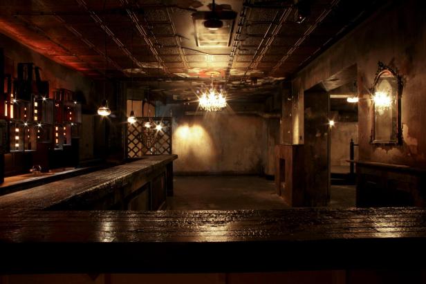 Ein dunkler, stimmungsvoller Raum mit Bar und Kronleuchter.