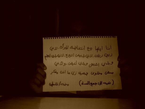 Eine Person hält ein Schild mit arabischer Schrift, das eine Botschaft der Frauenbewegung trägt.