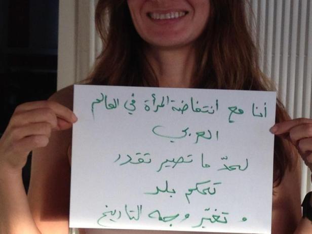 Eine Frau hält ein Schild mit arabischer Schrift hoch.