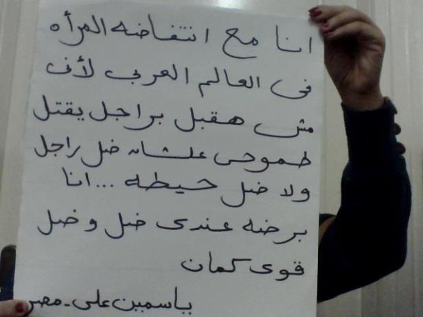 Eine Person hält ein Schild mit arabischer Schrift hoch.