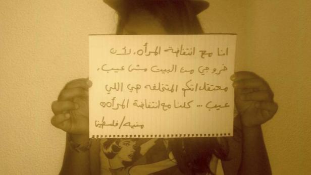 Eine Person hält ein Schild mit arabischer Schrift hoch.