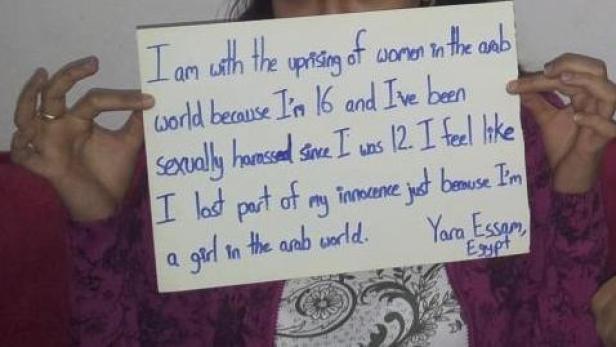 Eine junge Frau hält ein Schild mit einer handgeschriebenen Botschaft über sexuelle Belästigung in der arabischen Welt.