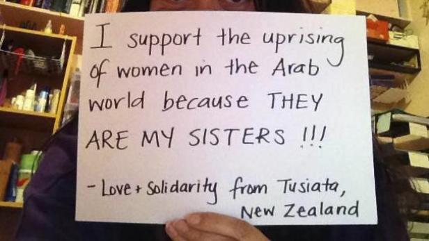 Eine Person hält ein Schild mit der Aufschrift „Ich unterstütze den Aufstand der Frauen in der arabischen Welt, weil SIE meine Schwestern sind!!! - Liebe + Solidarität aus Tusiata, Neuseeland“.
