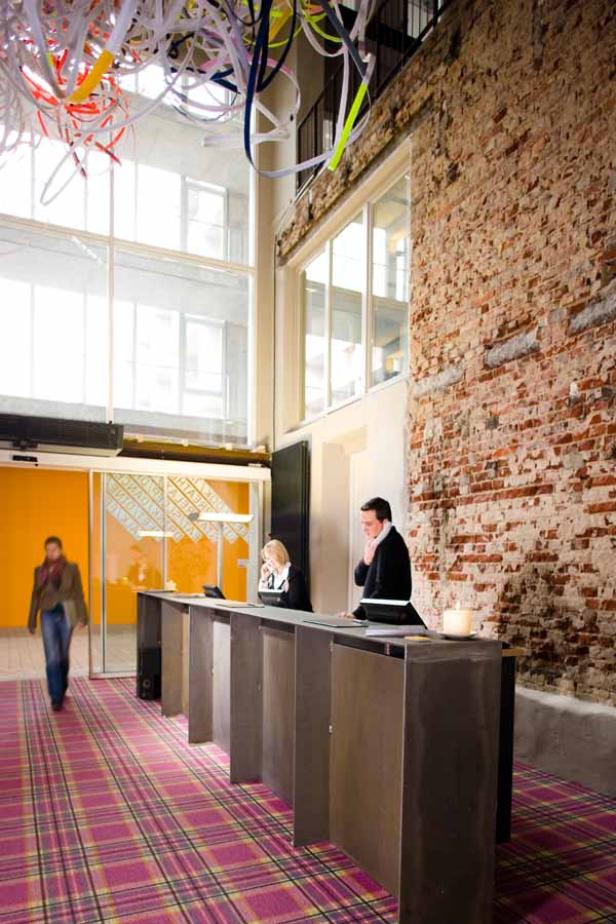 In einer Hotellobby stehen zwei Angestellte hinter einem langen Empfangstresen.