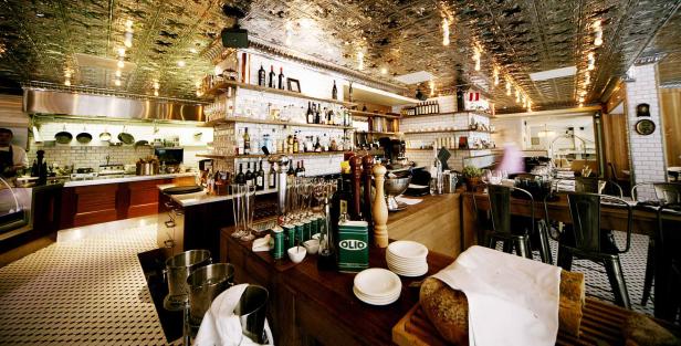 Innenansicht eines Restaurants mit offener Küche und Bar.