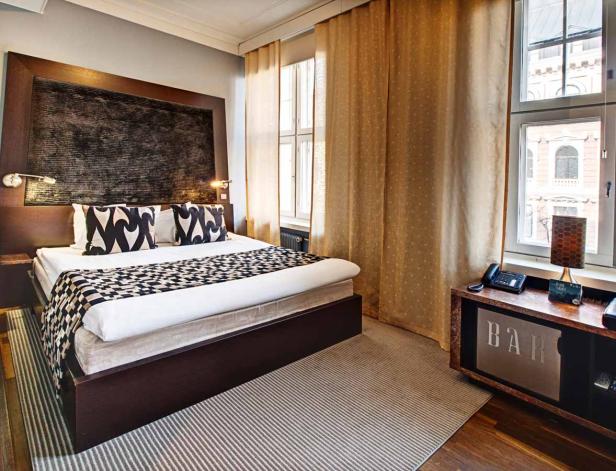 Ein Hotelzimmer mit einem Doppelbett, einem Nachttisch und einem Fenster mit Vorhängen.