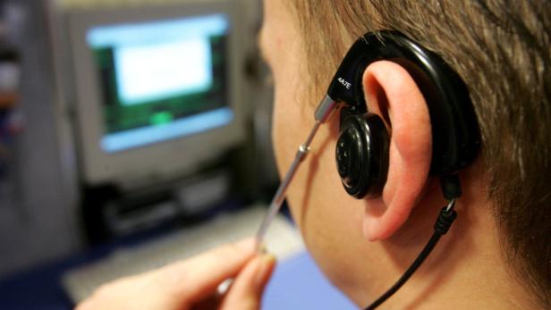 Eine Person trägt ein Headset und blickt auf einen Computerbildschirm.