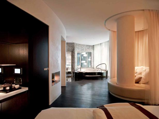 Ein luxuriöses Badezimmer mit Whirlpool, Sauna und einem runden Sofa um eine Säule.