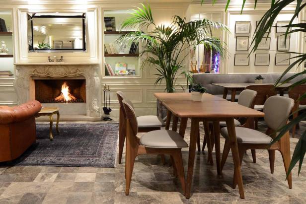 Ein gemütlicher Raum mit Kamin, Holztisch und Stühlen, dekoriert mit Pflanzen.