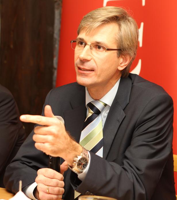 Ein Mann mit Brille gestikuliert während einer Rede mit einem Mikrofon in der Hand.