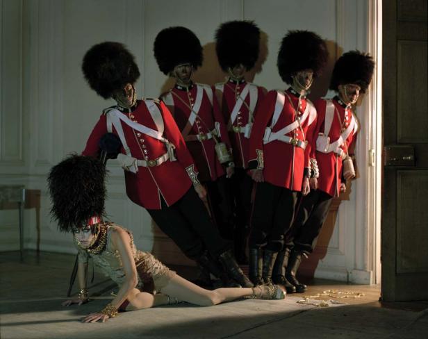 Eine Frau am Boden vor einer Reihe von britischen Gardesoldaten mit Bärenfellmützen.