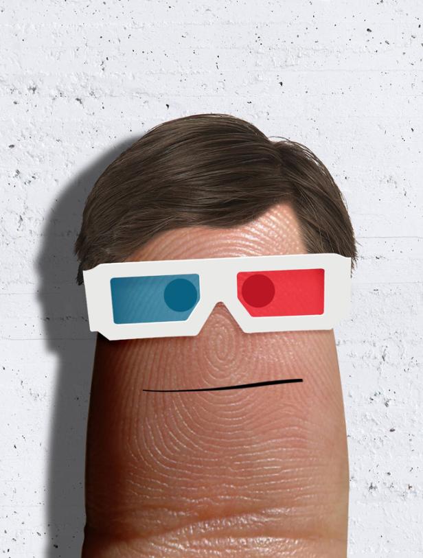 Ein Finger mit aufgemaltem Gesicht und 3D-Brille vor einer weißen Wand.