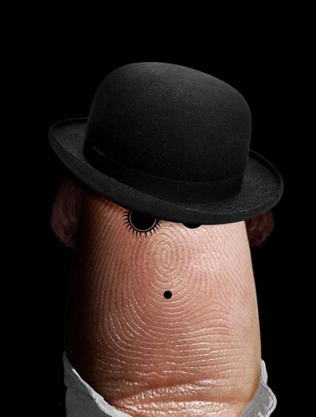 Ein Finger mit aufgemaltem Gesicht und Melone vor schwarzem Hintergrund.