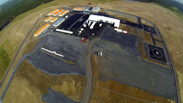 Eine Luftaufnahme einer Baustelle mit Baracken, Zelten und zwei Hubschrauberlandeplätzen.