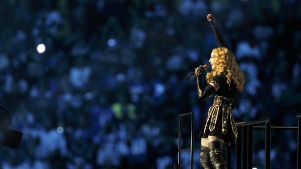 Madonna tritt während einer Show mit erhobenem Arm auf.
