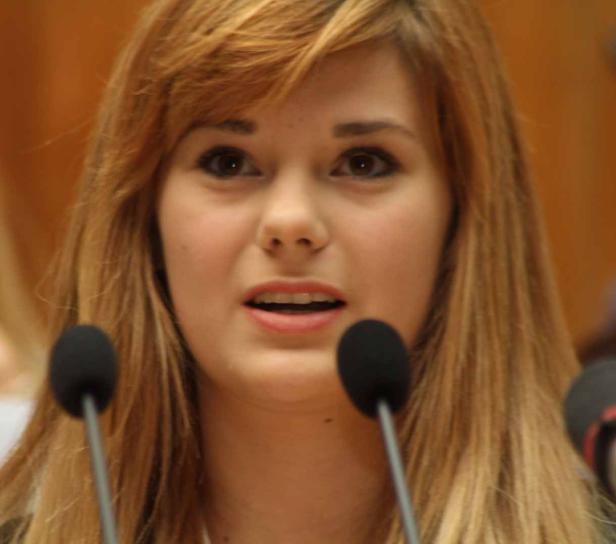 Eine junge Frau spricht vor Mikrofonen.