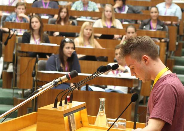 Ein junger Mann spricht vor einem Publikum in einem Hörsaal.