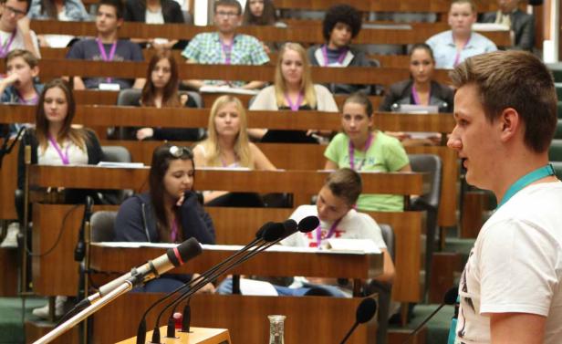 Ein junger Mann spricht vor einem Publikum in einem Hörsaal.