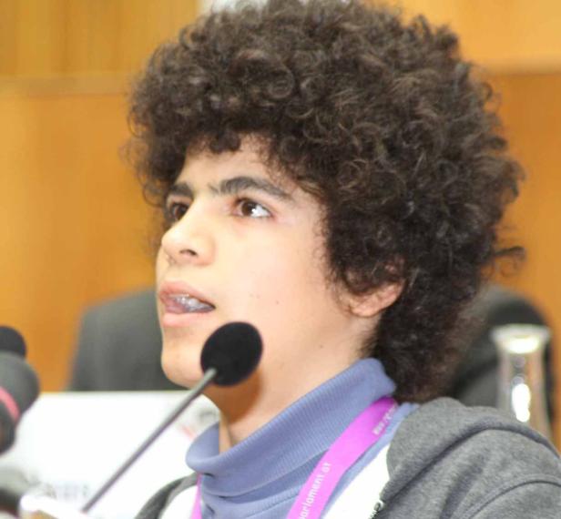 Ein junger Mann mit lockigem Haar spricht in ein Mikrofon.