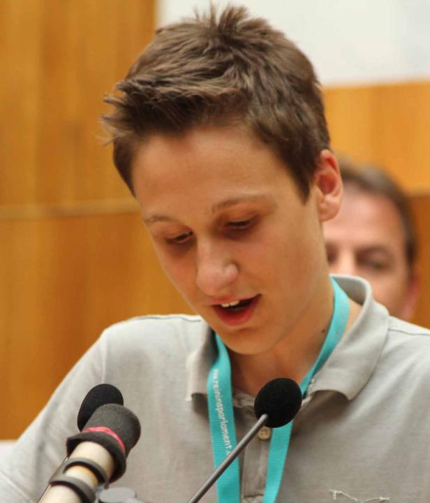 Ein junger Mann spricht an einem Mikrofon.