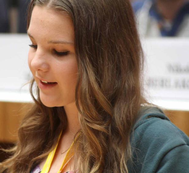 Eine junge Frau mit langen, gewellten Haaren schaut nach unten.