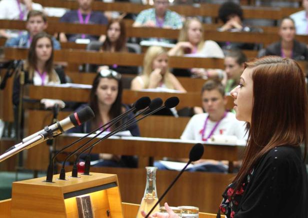 Eine junge Frau spricht vor einem Publikum in einem Hörsaal.