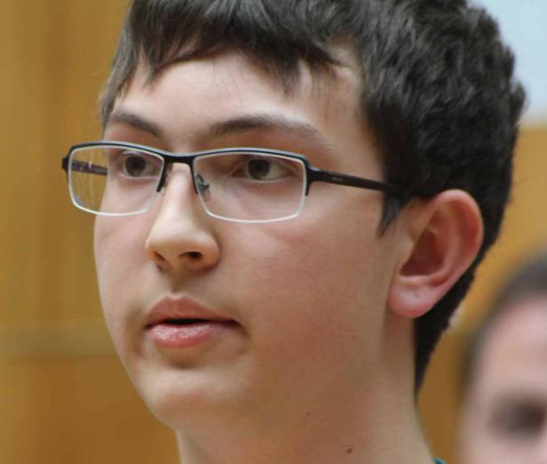 Ein junger Mann mit Brille schaut aufmerksam zur Seite.