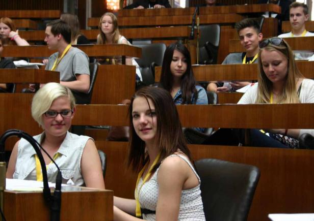 Junge Leute sitzen in einem holzvertäfelten Raum, möglicherweise bei einer Konferenz oder einer Schulung.