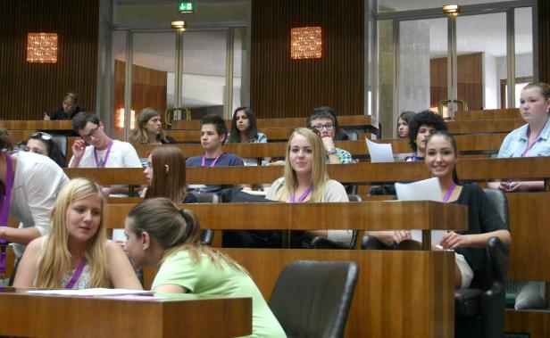 Eine Gruppe junger Leute sitzt in einem Hörsaal oder Konferenzraum.