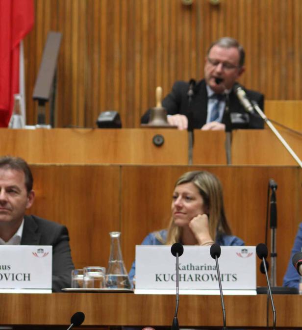 Katharina Kucharowits und andere Personen sitzen an einem Tisch mit Mikrofonen.