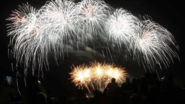 Eine Menschenmenge beobachtet ein Feuerwerk am Nachthimmel.