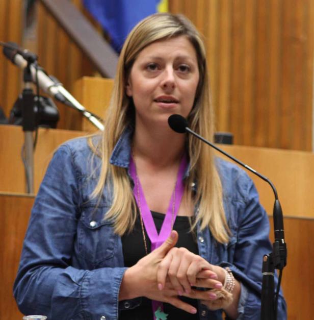 Eine Frau mit blonden Haaren spricht an einem Mikrofon.