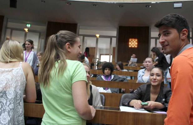 Zwei junge Leute unterhalten sich vor einem Publikum in einem Hörsaal.