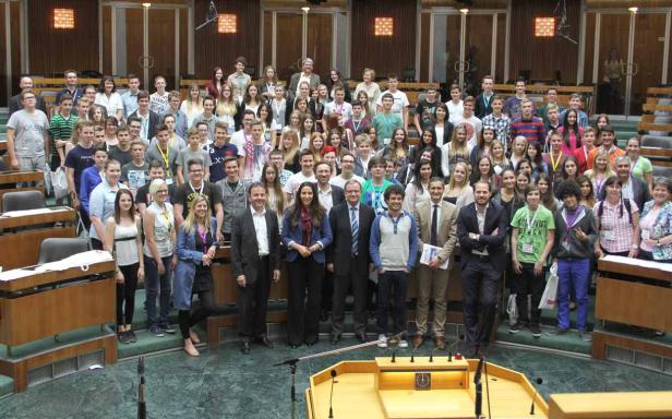 Eine große Gruppe von Menschen steht in einem Sitzungssaal.