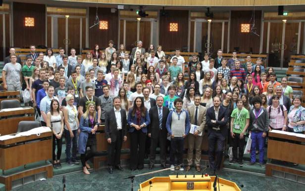 Eine große Gruppe von Menschen posiert in einem Sitzungssaal für ein Foto.