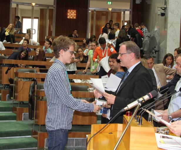 Ein junger Mann schüttelt einem älteren Mann in einem Konferenzraum die Hand.