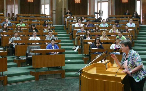 Eine Frau spricht vor einer Gruppe von Jugendlichen in einem Hörsaal.