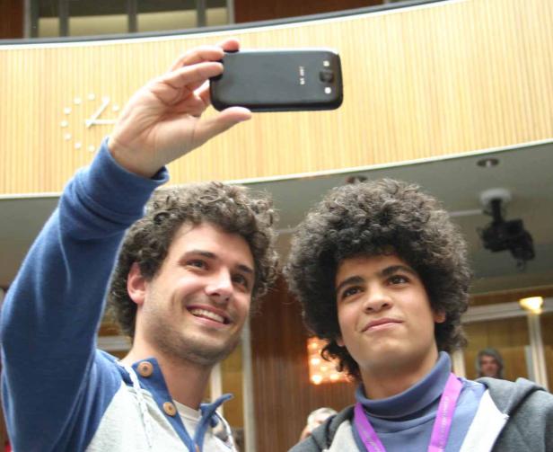 Zwei junge Männer mit lockigem Haar machen ein Selfie.