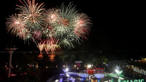 Feuerwerk erhellt den Nachthimmel über einem Vergnügungspark.