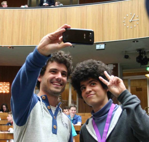 Zwei junge Männer machen ein Selfie in einem Hörsaal.