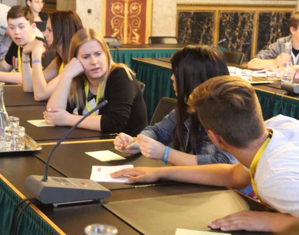 Jugendliche sitzen an einem Tisch während einer Konferenz oder eines Workshops.