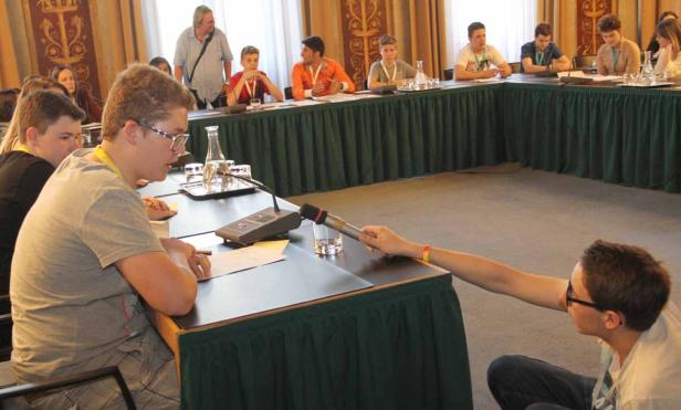 Jugendliche sitzen an einem Tisch und nehmen an einer Diskussion teil.