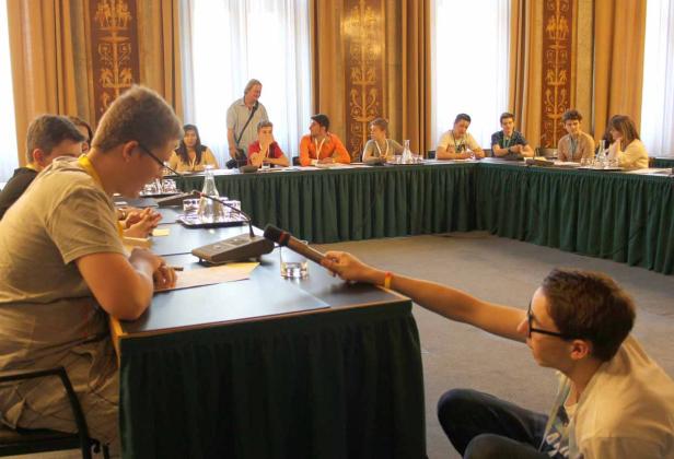 Eine Gruppe junger Leute sitzt an einem Tisch während einer Konferenz.