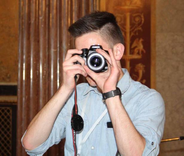 Ein junger Mann fotografiert mit einer Canon Kamera.